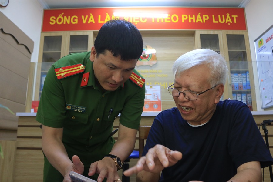 Trung tá Nguyễn Anh Tuấn hướng dẫn người dân đăng kí tài khoản định danh điện tử (Ảnh: Khánh An).