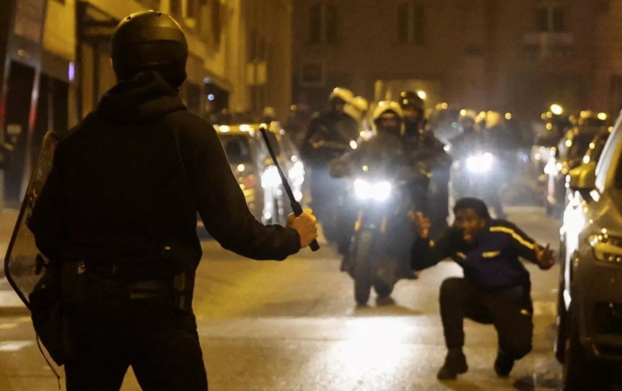Một người phản ứng trong khi cảnh sát cầm dùi cui tại một cuộc biểu tình ở Paris, Pháp, tối 2/7. Ảnh: Reuters