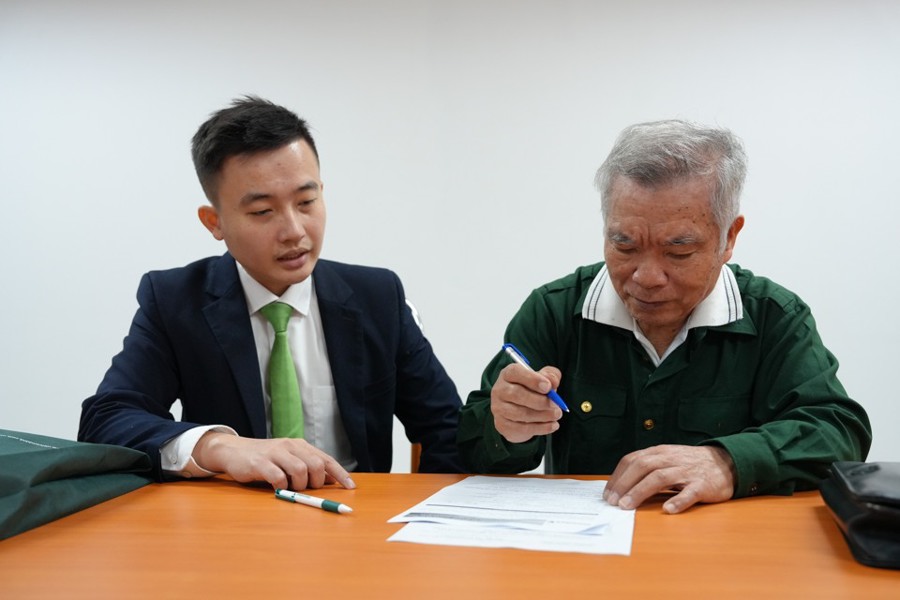 Ông Trần Kim Dung trú tại quận Long Biên được cán bộ ngân hàng hướng dẫn làm thủ tục mở tài khoản ngân hàng. Ảnh: Duy Khánh.