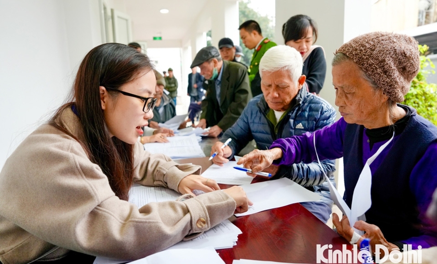 Lực lượng chức năng hỗ trợ người cao tuổi làm thủ tục mở tài khoản nhận chi trả tiền tiền trợ cấp hàng tháng. Ảnh: Duy Minh