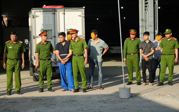 Cảnh sát dẫn giải Trần Nguyễn Hữu Thắng (áo đen), Nguyễn Chí Linh (quần đen) thực nghiệm hiện trường. Ảnh: Công an Tiền Giang