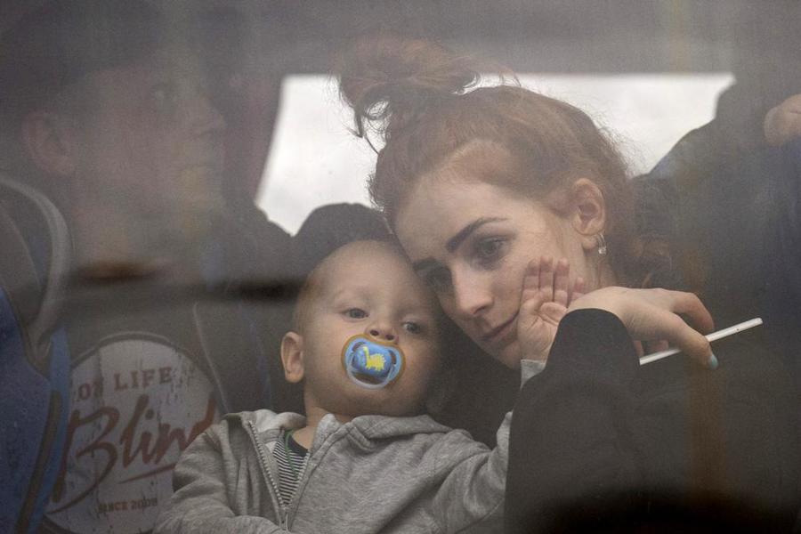 Một phụ nữ bế con bên trong xe buýt khi họ rời thủ đô Kiev, Ukraine, hôm 24/2. Ảnh: AP