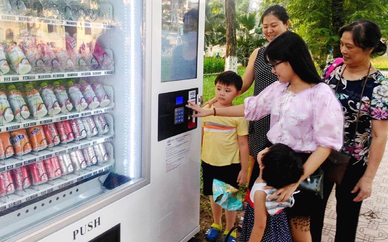 Người dân mua nước uống tại máy bán hàng tự động trên không gian đi bộ hồ Hoàn Kiếm. 