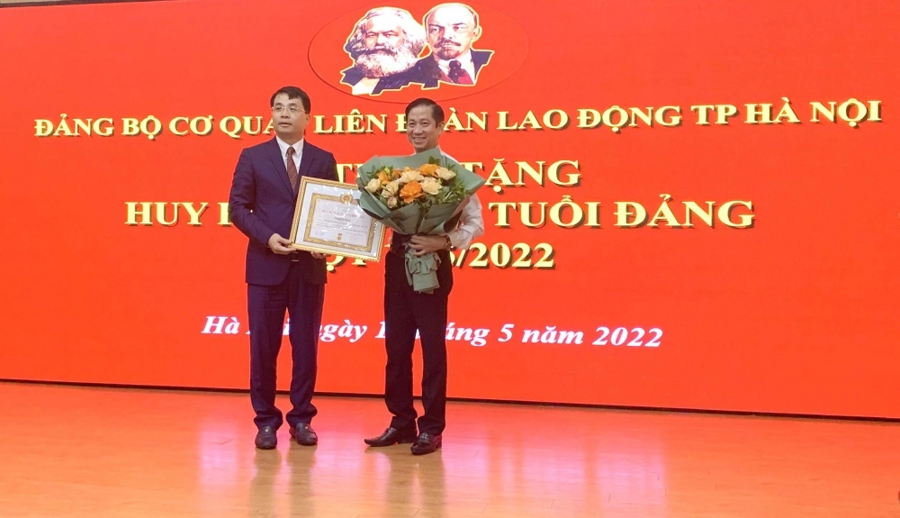 Bí thư Đảng ủy Khối các cơ quan TP Hà Nội Lê Minh Đức trao Huy hiệu 30 năm tuổi Đảng đợt 19/5/2022 và tặng hoa chúc mừng đồng chí Phạm Bá Vĩnh.
