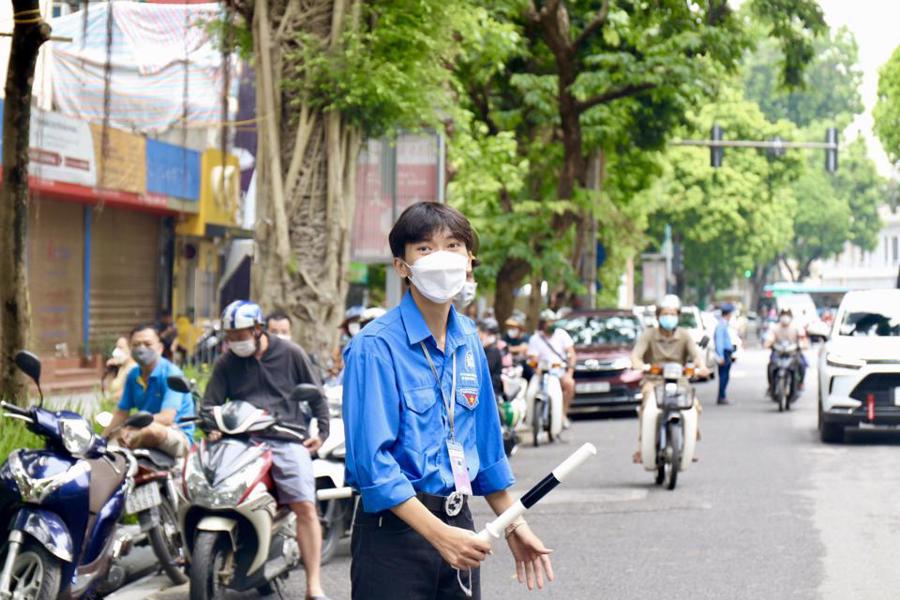 “Đội hình giao thông xanh”  phối hợp với lực lượng công an hướng dẫn, phân luồng, bảo đảm an toàn giao thông tại các điểm thi THPT năm 2022. Ảnh: Duy Khánh. 