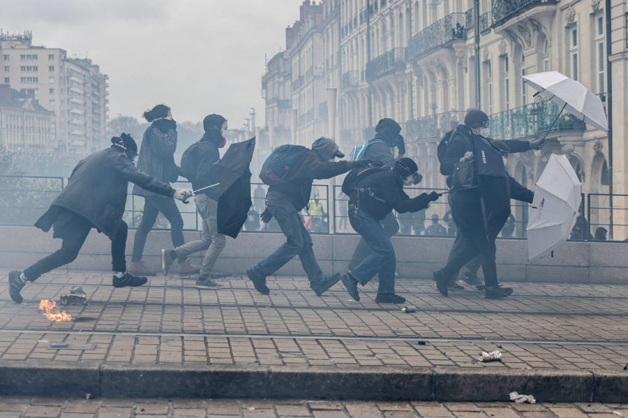 Người biểu tình che chắn hơi cay bằng ô trong khi đụng độ với cảnh sát chống bạo động, trong cuộc biểu tình ở Nantes, miền Tây nước Pháp, hôm 23/3. Ảnh: AP