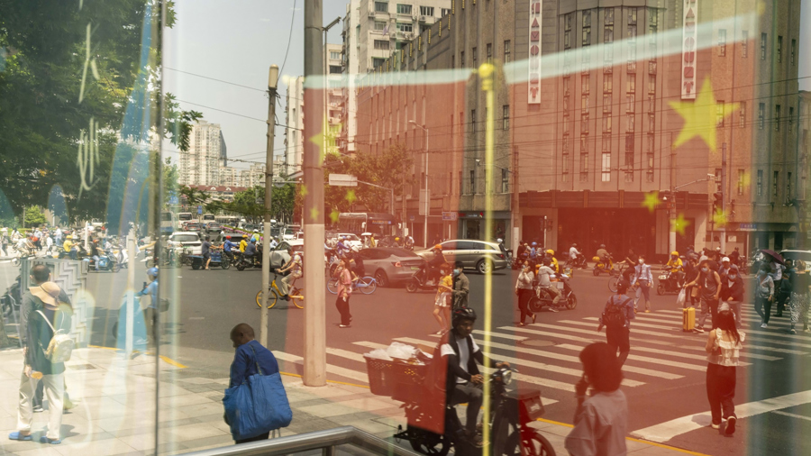 Cờ Trung Quốc và người đi bộ phản chiếu trên một cửa sổ ở Thượng Hải, tháng 6/2023. Ảnh: Bloomberg