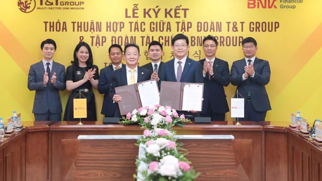 Chủ tịch Ủy ban Chiến lược T&T Group Đỗ Quang Hiển (bên trái) và Chủ tịch HĐQT kiêm Tổng Giám đốc Tập đoàn Tài chính BNK Bin Dae-in (bên phải) trao thỏa thuận hợp tác với sự chứng kiến của đại diện lãnh đạo hai Tập đoàn.