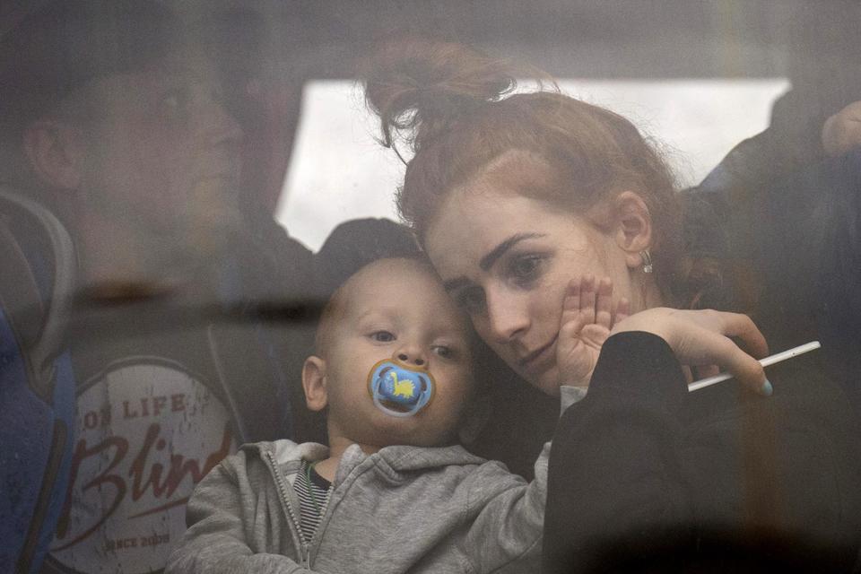 Một người phụ nữ &ocirc;m con khi đang tr&ecirc;n xe xu&yacute;t rời Kiev.