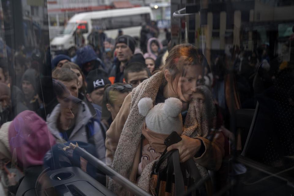 Một người phụ nữ &ocirc;m con l&ecirc;n xe rời thủ đ&ocirc; Kiev, ng&agrave;y 24/2. Ảnh: AP