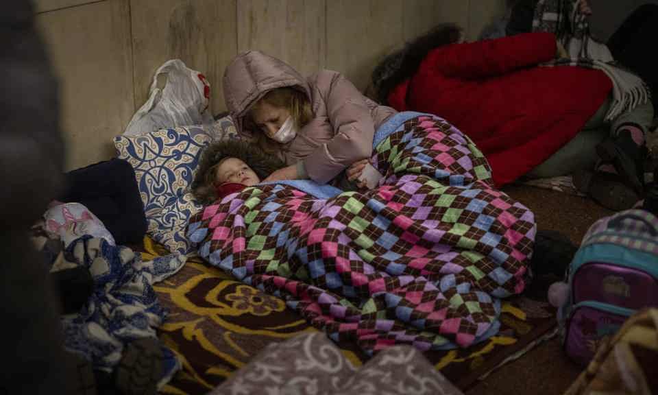 Một phụ nữ chăm s&oacute;c cho con trong hầm tr&uacute; bom tạm bợ ở Kyiv, Ukraine. Ảnh: AP