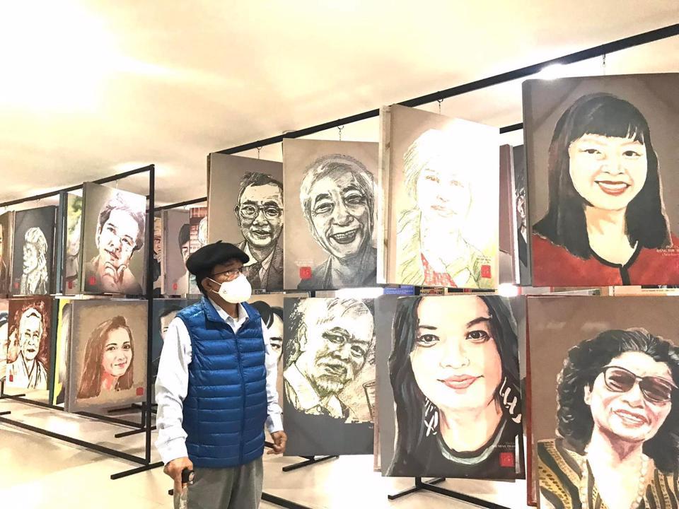Nhà báo Huỳnh Dũng Nhân ngắm nhìn các bức chân dung đồng nghiệp do ông thực hiện được trưng bày tại triển lãm
