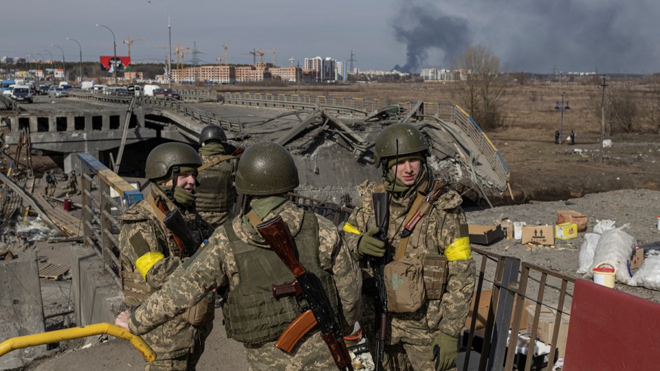Các binh sĩ Ukraine đứng bên một cây cầu bị phá hủy ở thị trấn Irpin, ngoại ô thủ đô Kiev. Ảnh Reuters