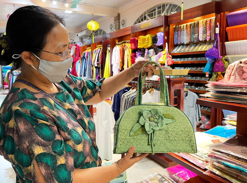 Nghệ nhân Nghiêm Thị Thu Hương giới thiệu sản phẩm túi cao cấp làm bằng lụa tơ tằm.