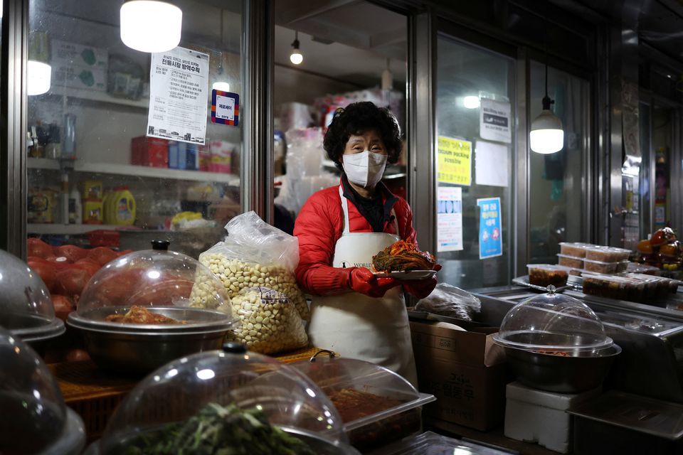 B&agrave; Choi Sun-hwa đang b&aacute;n kim chi tại cửa h&agrave;ng b&aacute;n đồ ăn k&egrave;m trong một khu chợ truyền thống ở Seoul, H&agrave;n Quốc. Ảnh: Reuters