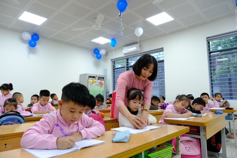 Giáo viên trường Tiểu học Thịnh Hào, quận Đống Đa hướng dẫn trẻ tập viết. Ảnh: Phạm Hùng