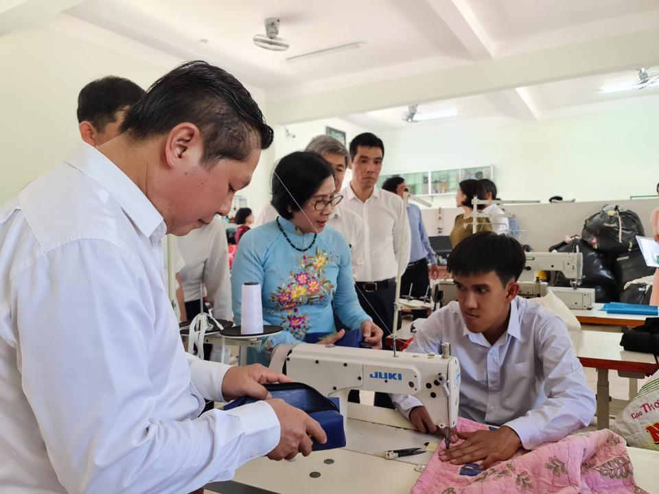 Bà Nguyễn Thị Thu Hà - Giám đốc Trung tâm nuôi dạy trẻ khuyết tật Võ Hồng Sơn giới thiệu với các quan khách về sản phẩm của lớp thực hành may. Ảnh: Đỗ Quyên