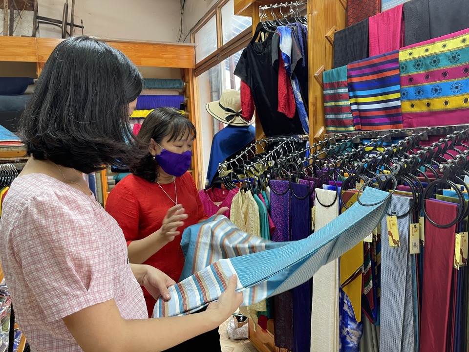 Nghệ nhân Trần Thị Ngọc Lan(áo sẫm) đang giới thiệu sản phẩm lụa tơ tằm với khách hàng. Ảnh: Bích Hời