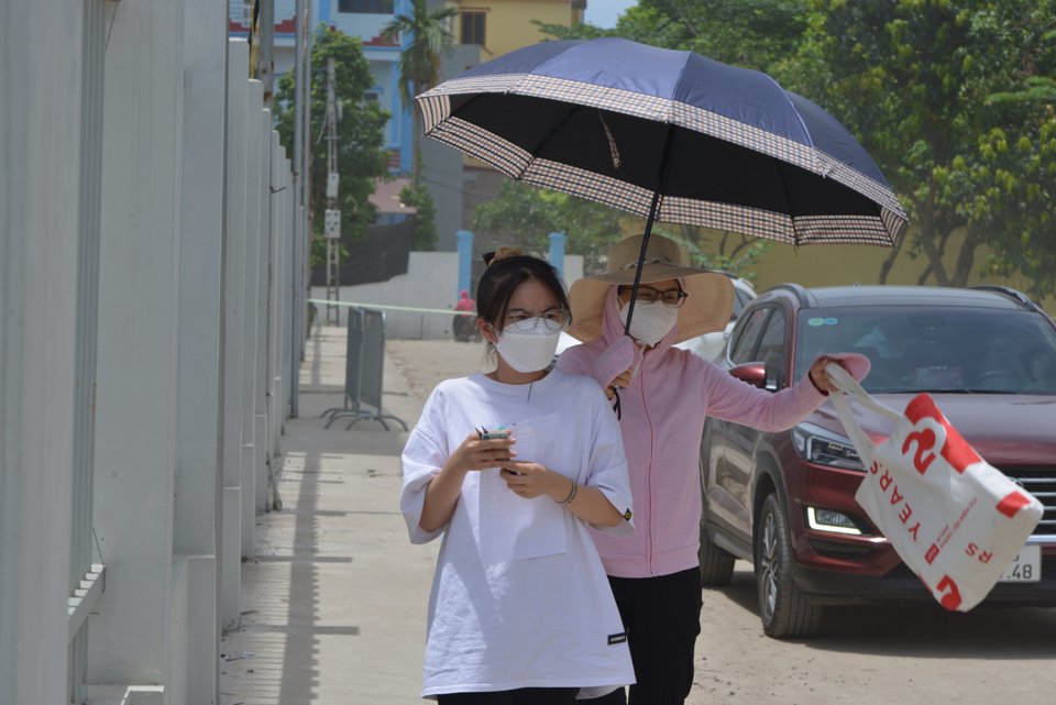 V&igrave; trời n&oacute;ng n&ecirc;n phụ huynh phải d&ugrave;ng &ocirc; v&agrave; mũ che cho c&aacute;c sĩ tử, đảm bảo sức khỏe tham gia kỳ thi. Ảnh: Phạm H&ugrave;ng.