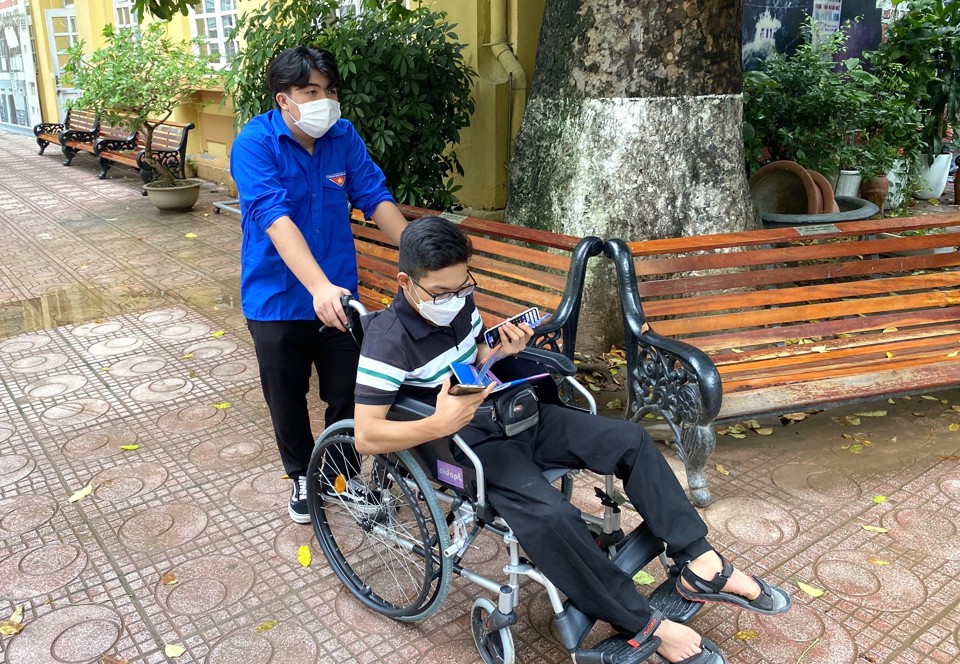 Một thí sinh khuyết tật được hỗ trợ đến điểm thi THCS Nguyễn Công Trứ (quận Ba Đình)