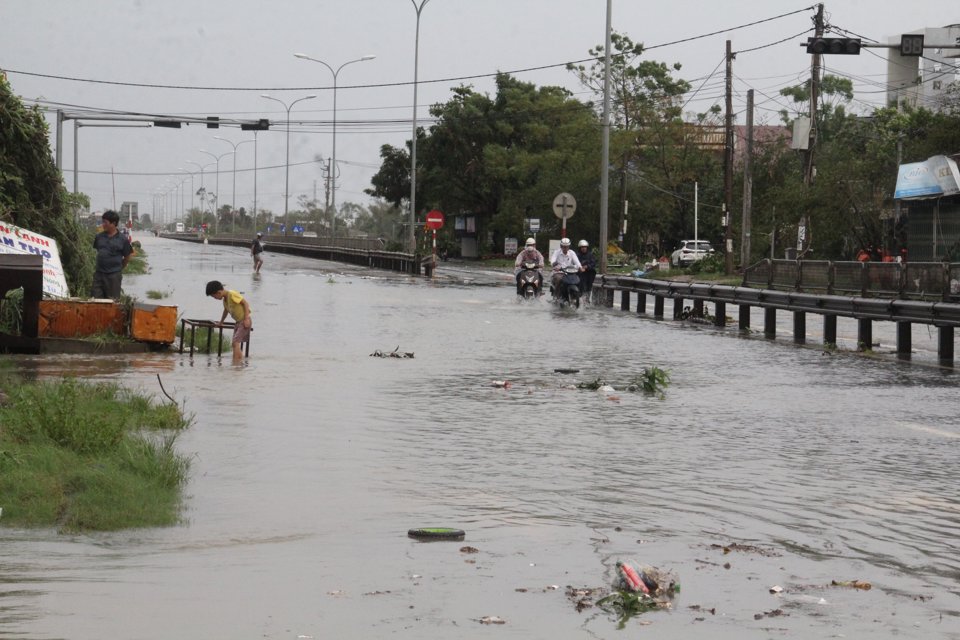 Nước chảy tr&agrave;n qua tuyến Quốc lộ 1 khiến việc đi lại rất kh&oacute; khăn