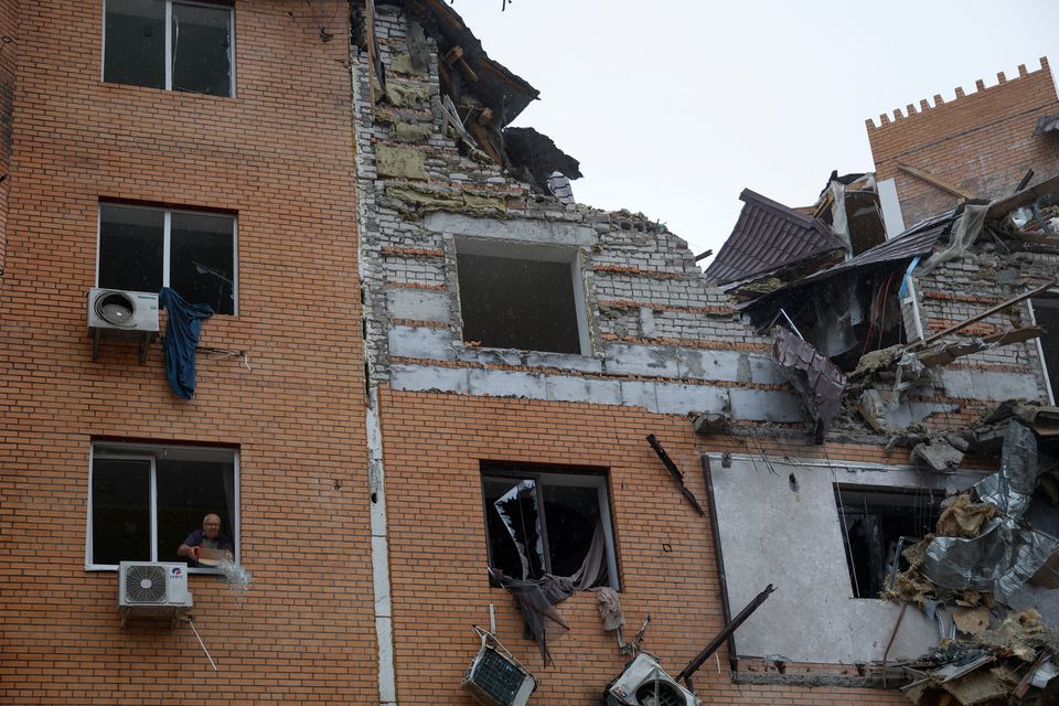 Một người đ&agrave;n &ocirc;ng địa phương n&eacute;m c&aacute;c mảnh vỡ từ cửa sổ trong một t&ograve;a nh&agrave; d&acirc;n cư bị hư hại nặng nề do tấn c&ocirc;ng t&ecirc;n lửa ở Mykolaiv, Ukraine ng&agrave;y 23/10/2022. Ảnh: Reuters