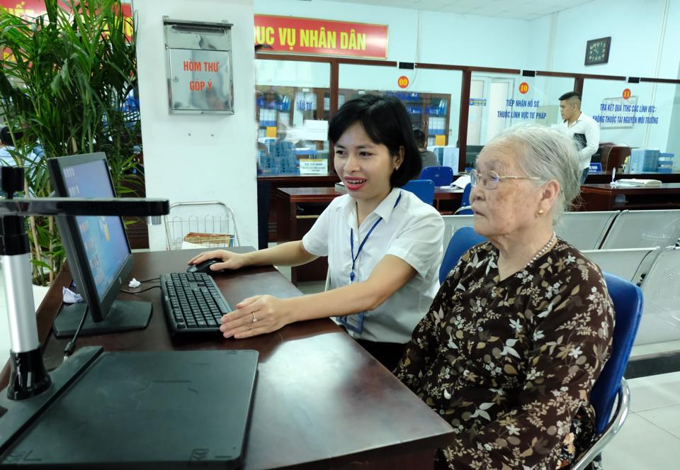 C&aacute;n bộ UBND quận Bắc Từ Li&ecirc;m hướng dẫn người cao tuổi l&agrave;m thủ tục h&agrave;nh ch&iacute;nh. Ảnh: C&ocirc;ng H&ugrave;ng.