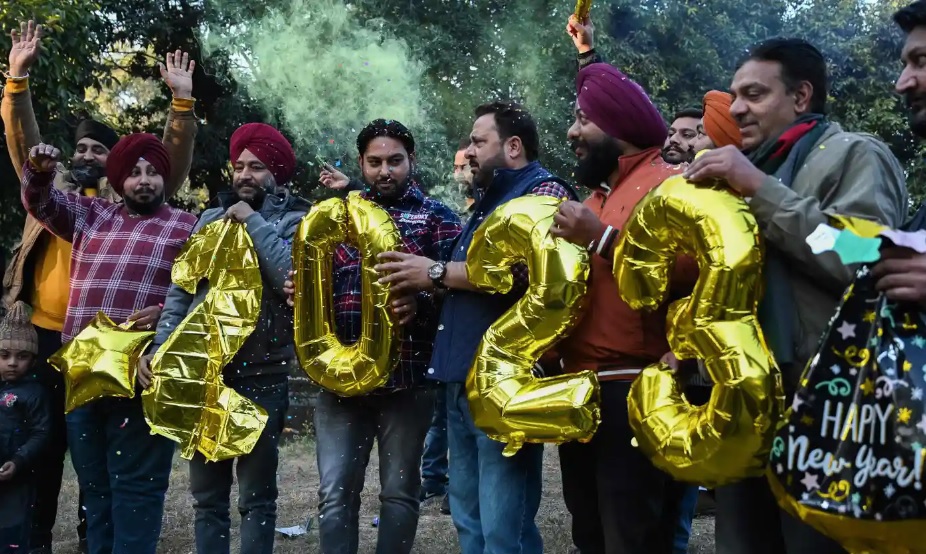 Người d&acirc;n cầm những quả b&oacute;ng bay h&igrave;nh chữ số trong lễ đ&oacute;n giao thừa ở Amritsar v&agrave;o ng&agrave;y 31/12 năm 2022. Ảnh: AFP
