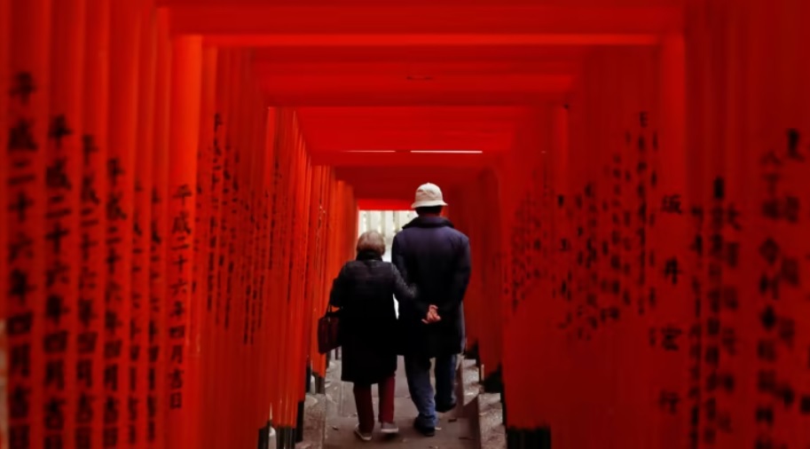Một cặp vợ chồng gi&agrave; đi bộ qua một ng&ocirc;i đền ở Tokyo v&agrave;o th&aacute;ng 12. Ảnh: Reuters