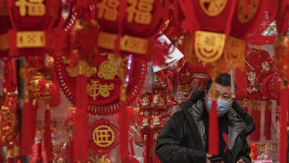 Một khách hàng đeo khẩu trang mua đồ trang trí Tết trên vỉa hè ở Bắc Kinh, Trung Quốc, tháng 1/2023. Ảnh: AP