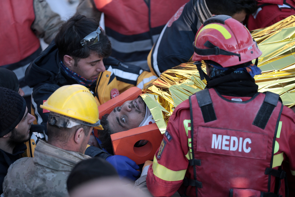 Nh&oacute;m cứu hộ đặt anh Mustafa nằm l&ecirc;n c&aacute;ng v&agrave; quấn một chiếc chăn trong khi chờ xe cứu thương đến h&ocirc;m 12/2. Ảnh: CNN