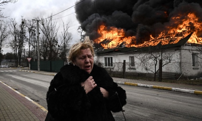 Một phụ nữ bỏ chạy trước ng&ocirc;i nh&agrave; đang ch&aacute;y ở th&agrave;nh phố Irpin, Ukraine. Ảnh: AFP
