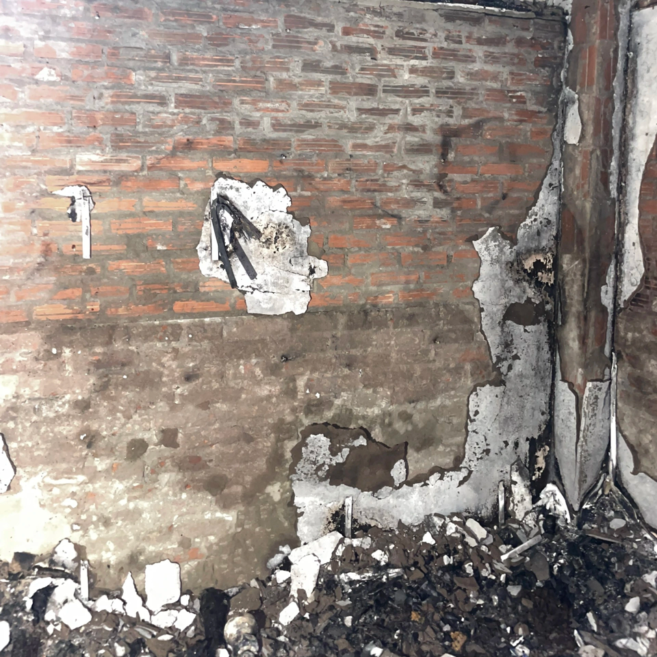 Tường ngôi nhà bị bong chóc sau cháy. Nhiều vật dụng bị thiêu rụi.