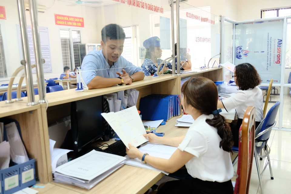 Cán bộ UBND huyện Sóc Sơn hướng dẫn người dân giải quyết thủ tục hành chính. Ảnh: Công Hùng