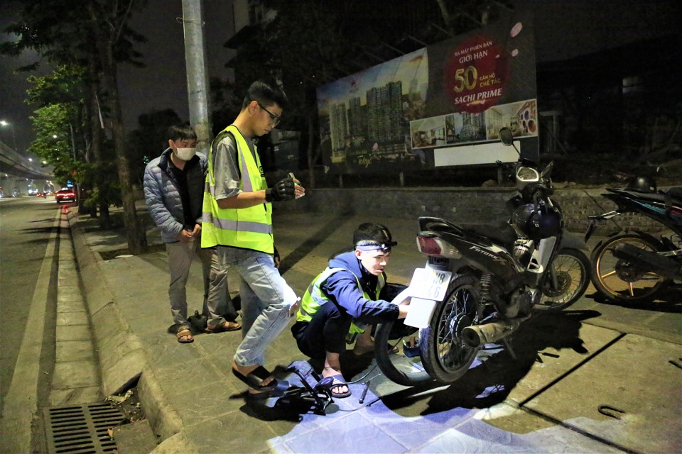 Các thành viên đội Cứu hộ Hà Nội sửa xe miễn phí trong đêm cho người đi đường. Ảnh: Phạm Công