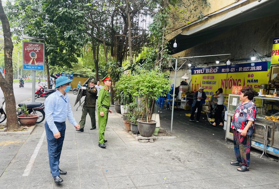 Lực lượng chức năng phường Thanh Xuân Bắc xử lý các trường hợp lấn chiếm lòng đường, vỉa hè, dành lại vỉa hè cho người đi bộ. Ảnh: Thái San