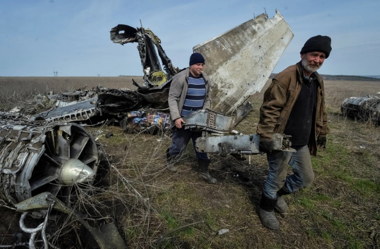 Cư d&acirc;n địa phương b&ecirc; kim loại phế liệu được thu thập gần một chiếc m&aacute;y bay qu&acirc;n sự bị ph&aacute; hủy ở v&ugrave;ng Kharkiv của Ukraine. Ảnh: Reuters