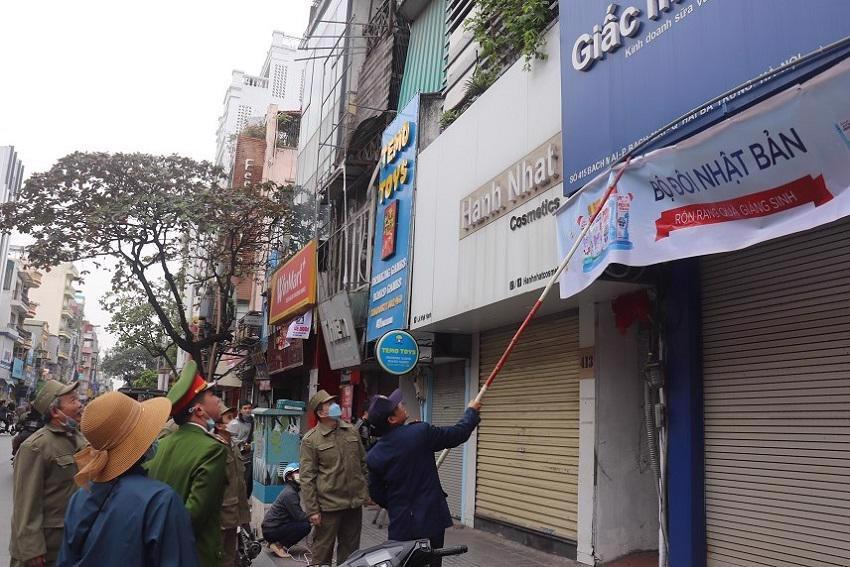 Lực lượng chức năng quận Hai Bà Trưng kiểm tra, xử lý các trường hợp kinh doanh vi phạm quy định về hoạt động quảng cáo tại các tuyến phố chính trên địa bàn. Ảnh: Linh Nguyễn