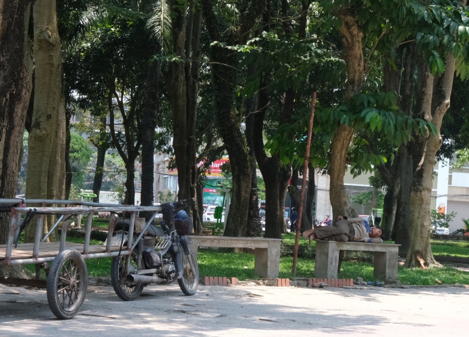 Người đ&agrave;n &ocirc;ng l&agrave;m nghề vận chuyển h&agrave;ng nằm ghế đ&aacute; c&ocirc;ng vi&ecirc;n nghỉ tạm giữa đỉnh điểm nắng n&oacute;ng.