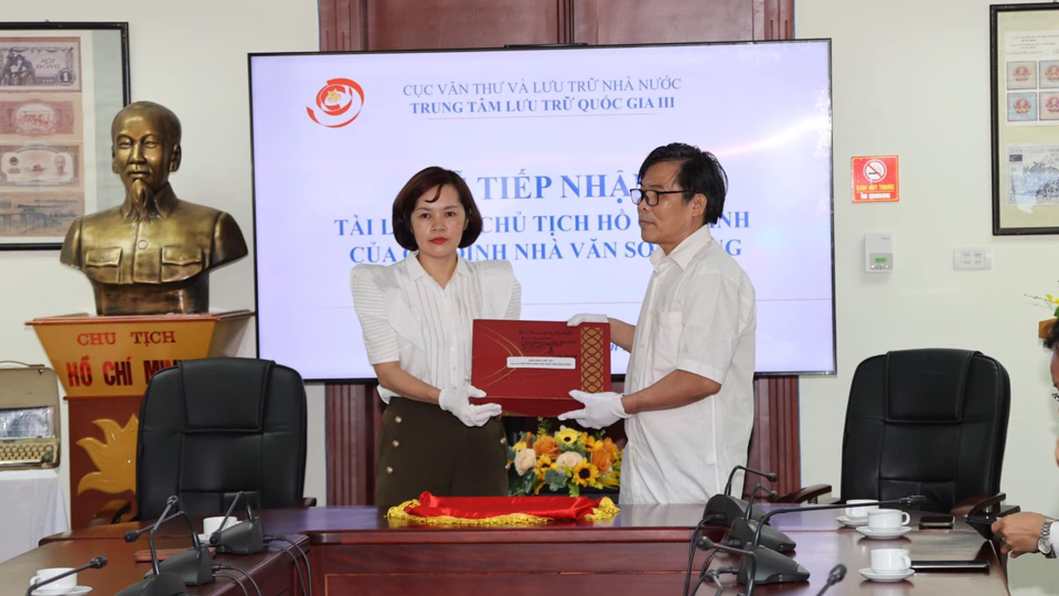 Con trai nhà văn Sơn Tùng (phải) trao tặng tài liệu cho đại diện Trung tâm Lưu trữ quốc gia III. Ảnh TTLTLQG