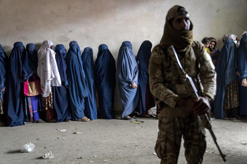 Một chiến binh Taliban đứng g&aacute;c khi những người phụ nữ chờ nhận tiếp tế lương thực từ một nh&oacute;m viện trợ nh&acirc;n đạo ở Kabul, Afghanistan, ng&agrave;y 23/5/2023. Ảnh: AP
