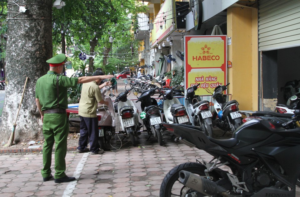 Lực lượng C&ocirc;ng an phường B&aacute;ch Khoa nhắc nhở c&aacute;c hộ kinh doanh để phương tiện đ&uacute;ng nơi quy định.