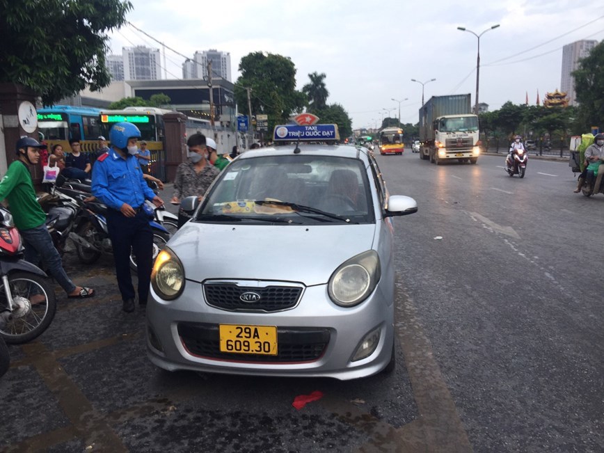 Lực lượng Đội Thanh tra cơ động xử lý xe taxi dừng, đỗ trước cửa bến xe Nước Ngầm. Ảnh: Phạm Công