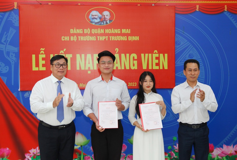 Bí thư Quận ủy, Chủ tịch HĐND quận Hoàng Mai Nguyễn Quang Hiếu (bên trái) trao Quyết định kết nạp đảng viên cho 2 học sinh lớp 12 tại Trường THPT Trương Định. Ảnh: Đông Hùng