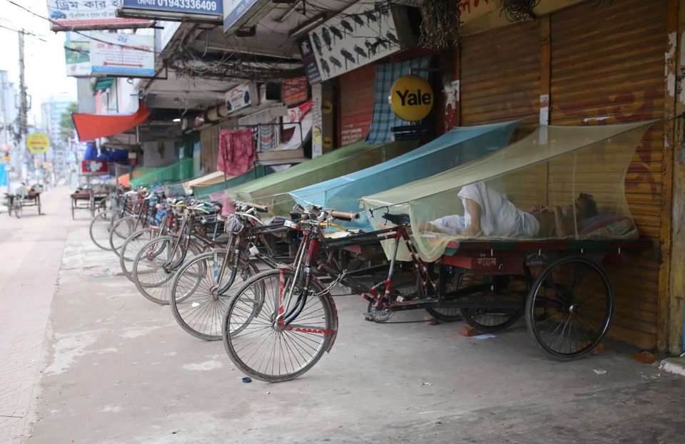 Người v&ocirc; gia cư ngủ tr&ecirc;n xe trang bị m&agrave;n chống muỗi ở thủ đ&ocirc; Dhaka, Bangladesh. Ảnh: New York Post