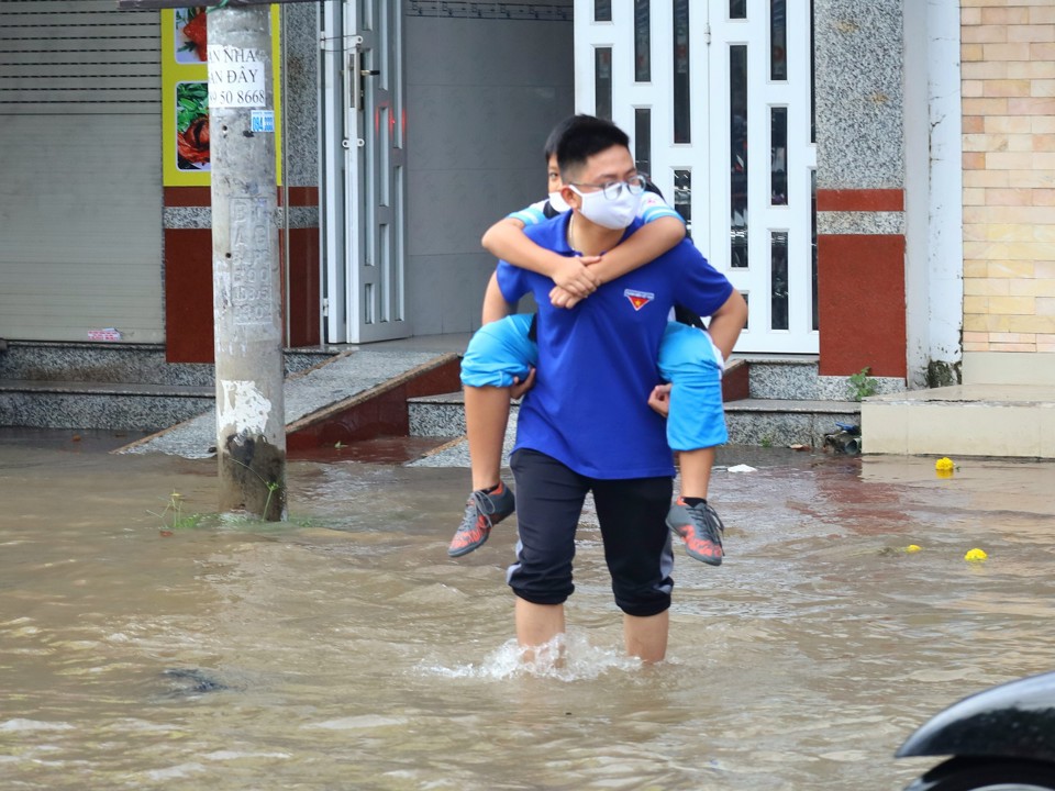 Đo&agrave;n vi&ecirc;n quận Ninh Kiều c&otilde;ng học sinh qua đoạn ngập s&acirc;u để đến trường.