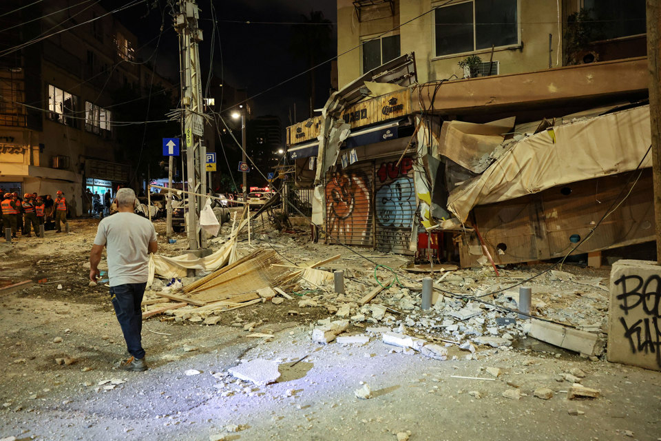 Một người đ&agrave;n &ocirc;ng đi dọc con phố đầy mảnh vụn ở Tel Aviv, Israel, sau khi nơi đ&acirc;y bị tr&uacute;ng t&ecirc;n lửa bắn từ Gaza v&agrave;o ng&agrave;y 7/10. Ảnh: AFP