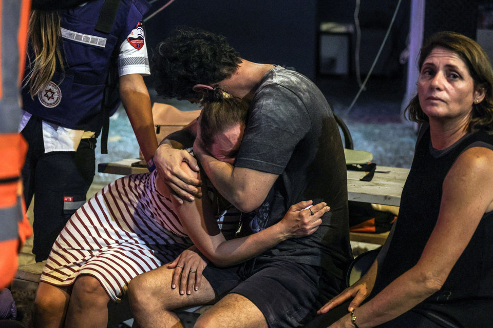 Người dân tại một địa điểm ở Tel Aviv (Israel), nơi một tên lửa phóng từ Gaza rơi xuống đất hôm 7/10. Ảnh: AFP