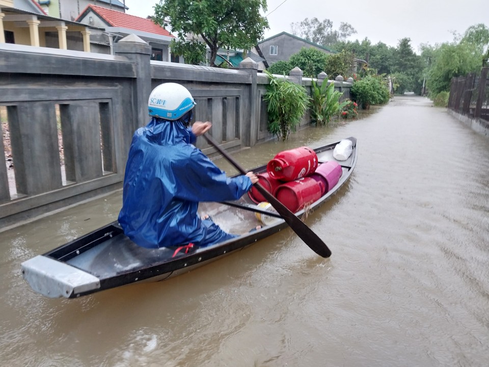 Người d&acirc;n sử dụng thuyền để di chuyển qua tuyến đường bị ngập tại huyện Quảng Điền.