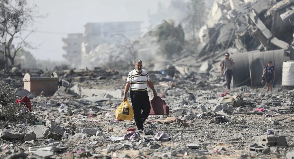Người Palestine đi ngang qua những toà nhà bị phá huỷ trong vụ bắn phá của Israel vào al-Zahra, ngoại ô thành phố Gaza, hôm 20/10/2023. Ảnh: AP